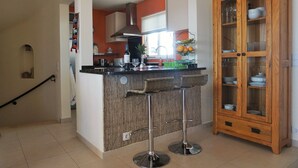 Une cuisine avec un coin bar, un meuble en bois doté de portes en verre et un escalier.
