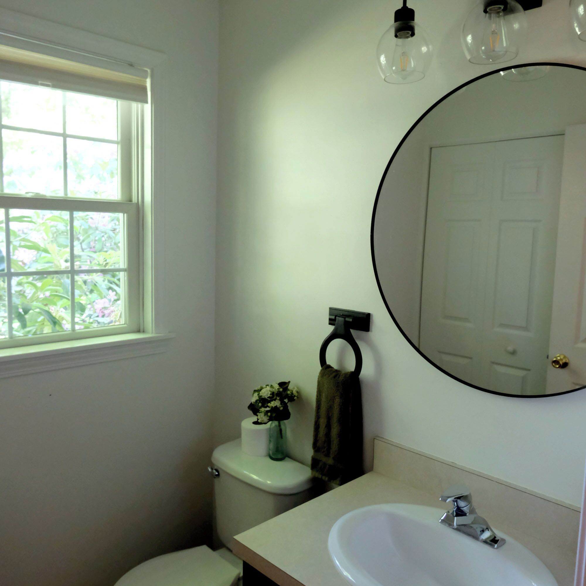 A bathroom with a toilet, sink, and a window.