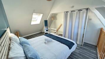 A bedroom with a bed, a window, a mirror, and a door.