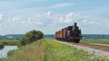 A steam locomotive on a railway track with a rural landscape in the background.