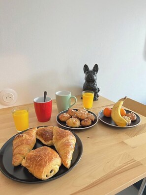 A breakfast table with croissants, a French Bulldog figurine, and a plate of fruit. - COSY CASA. (Abbeville)