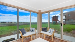 Un balcon avec des fauteuils en osier et une vue sur un terrain de jeux et des immeubles.