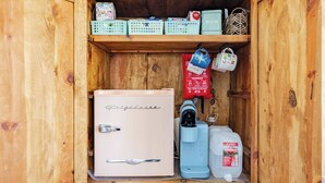 Ein Holzschrank mit einem Kühlgerät im Vintage-Stil, einer Kaffeemaschine und verschiedenen Küchenutensilien.