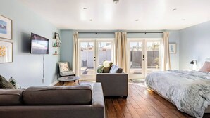 Ein modernes Schlafzimmer mit einem großen Bett, einer Couch, einem Sessel und einem Fernseher.