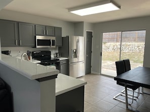 Une cuisine moderne avec des meubles gris, des appareils en acier inoxydable et un grand îlot central.
