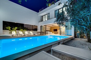 Ein moderner Außenpool mit Liegestühlen und Essbereich.