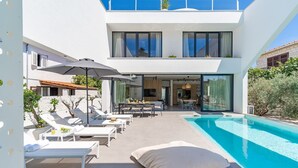 Una casa moderna de dos pisos con piscina, mobiliario exterior y zona de comedor.