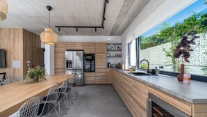 Una cocina moderna con una isla de madera, electrodomésticos de acero inoxidable y un ventanal con vistas a zonas verdes.