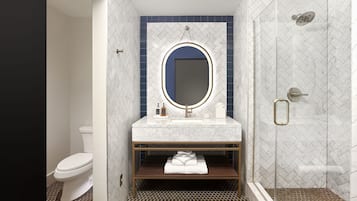A modern bathroom with a white toilet, a vanity with a mirror, and a shower area.
