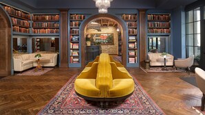 Una biblioteca con estanterías, un sillón amarillo y una araña.