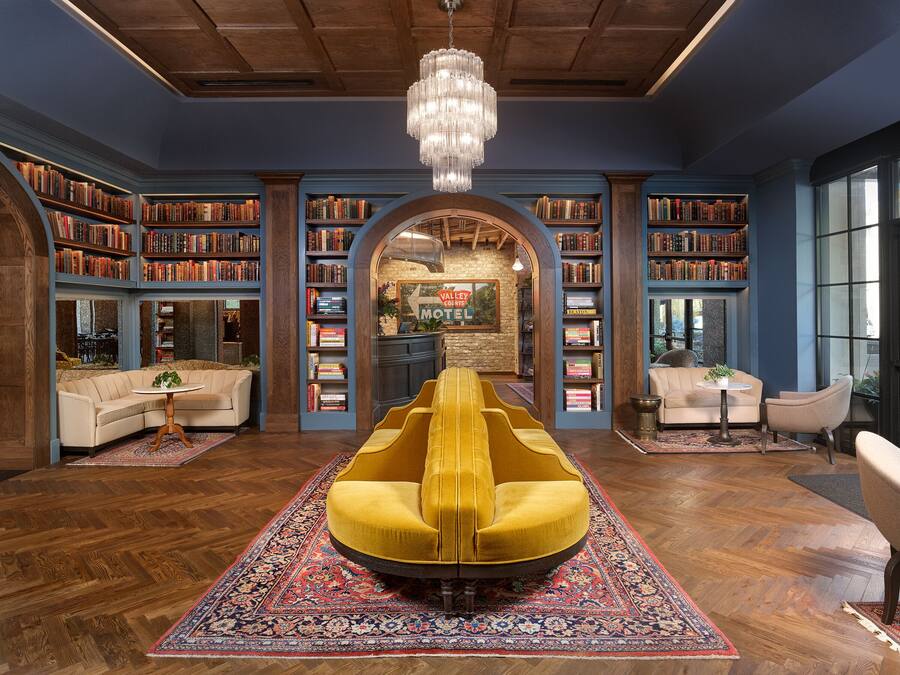 A library with bookshelves, a yellow armchair, and a chandelier.