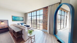 A modern living room with a large window, a sofa, a small table with a plant, and a lamp. - The Restoration Asheville (Asheville)
