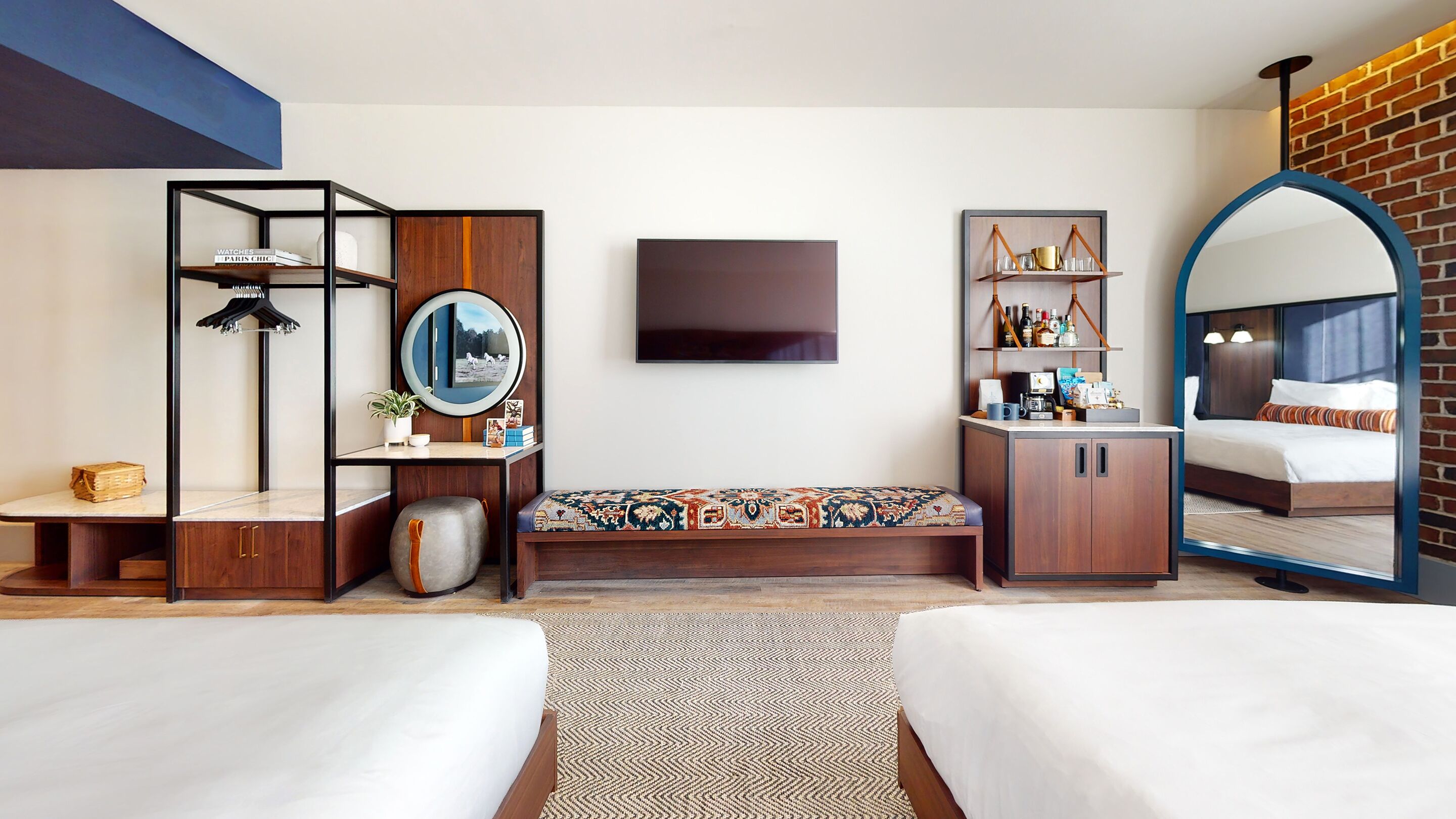Una habitación de hotel moderna con una cama grande, un sofá, un escritorio con espejo, un televisor y una estantería.