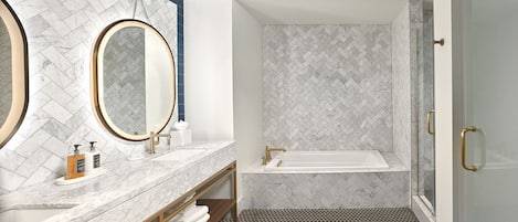 Une salle de bain moderne avec un meuble-lavabo en marbre, un grand miroir, une baignoire et un espace douche.