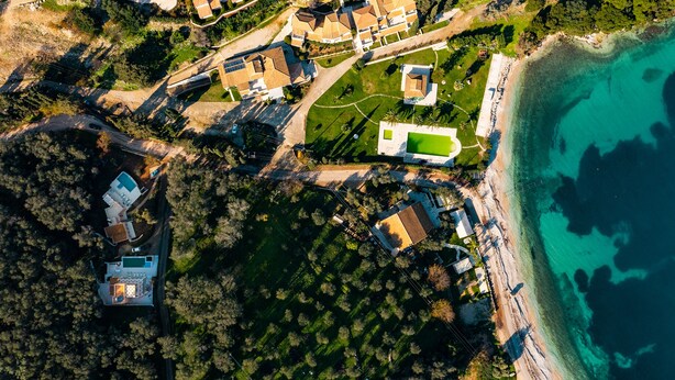 Oversigtsbillede af et kystnære boligområde med huse, en strand og en golfbane.