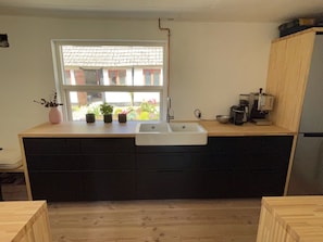 Una cocina moderna con un amplio ventanal, un lavamanos y una cafetera.