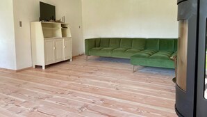 Een kamer met een groene hoekbank, een wit kastje en een houten vloer.
