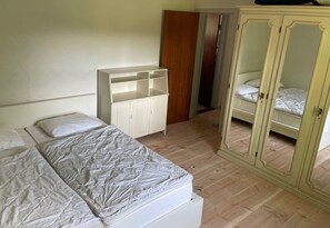 Une chambre à coucher comprenant un lit, une armoire et une porte donnant sur une autre pièce.
