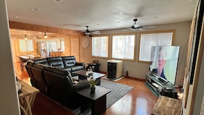 A spacious living room with a fireplace, a television, and a dining area in the background. - 5 bed 5 bath cabin 5 min to the Slopes or Mountain Biking (Truckee)