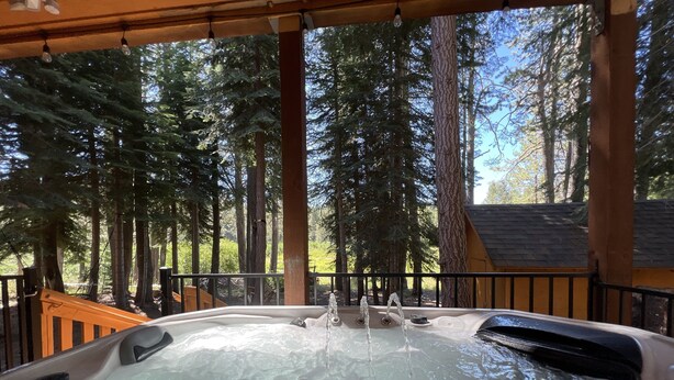 A hot tub with water jets, surrounded by tall trees and a wooden deck. - 5 bed 5 bath cabin 5 min to the Slopes or Mountain Biking (Truckee)