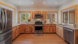 A spacious kitchen with wooden cabinets, stainless steel appliances, and large windows. - 5 bed 5 bath cabin 5 min to the Slopes or Mountain Biking (Truckee)