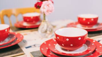 A table set with red and white polka-dotted tableware, including bowls and plates, and a vase with pink flowers.