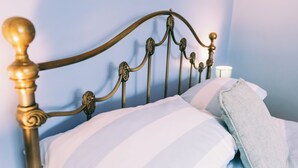 A bed with a metal headboard, white striped pillows, and a light blue blanket. - Cozy Scarning Apartment for Two (Dereham)