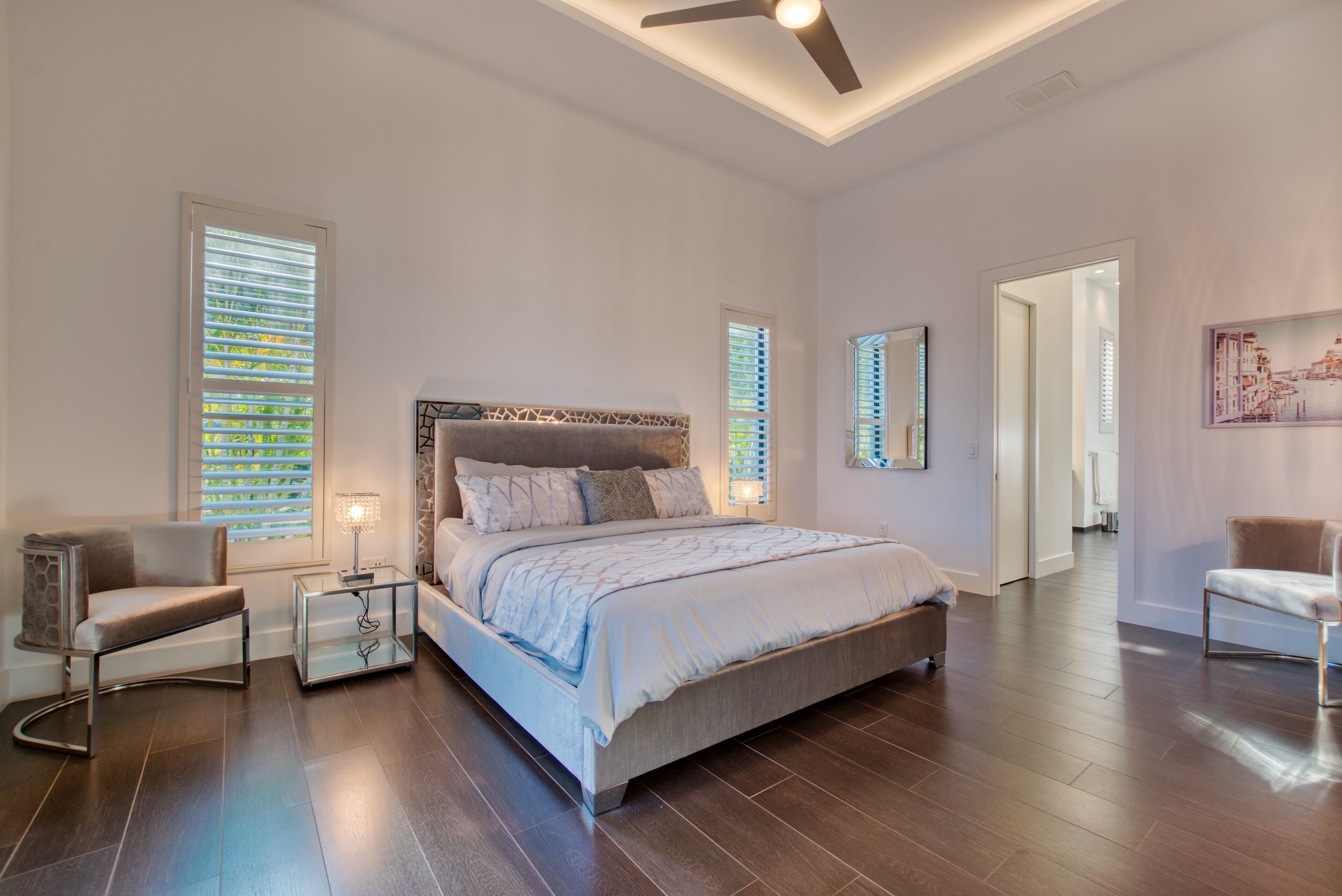 A spacious bedroom with a large bed, a modern chair, and a bedside table.