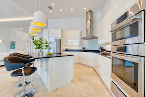 Enjoy cooking in this kitchen with sleek appliances, a central island, and white cabinetry.