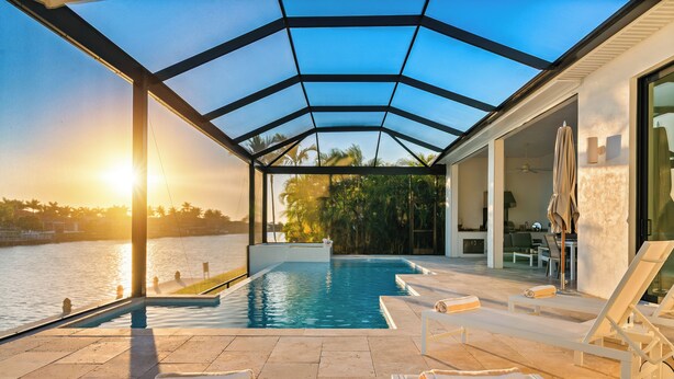 Ein moderner Poolbereich im Freien mit Liegestühlen und einer Glaskuppel, mit Blick auf ein Gewässer.