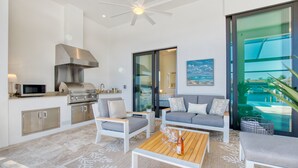 Eine moderne Küche mit eingebauter Mikrowelle und Herd, einem Deckenventilator und einer großen Glasdoor, die zu einem Poolbereich führt.