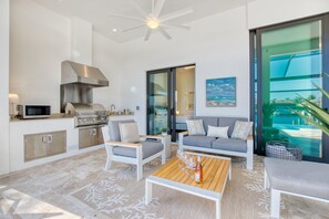 Enjoy a comfortable stay in this stylish living space with a sleek kitchen, comfortable sofa, and balcony overlooking the pool.