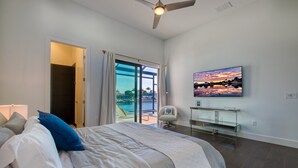 Ein Schlafzimmer mit Bett, Fernseher und Blick auf einen Pool.