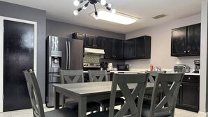 A modern kitchen with dark cabinetry, stainless steel appliances, and a central island with seating.