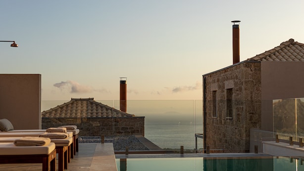 A poolside area with lounge chairs and a view of the sea. - Patio Villas (West Mani)