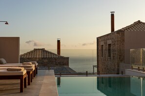 A poolside area with lounge chairs and a view of the sea. - Patio Villas (West Mani)