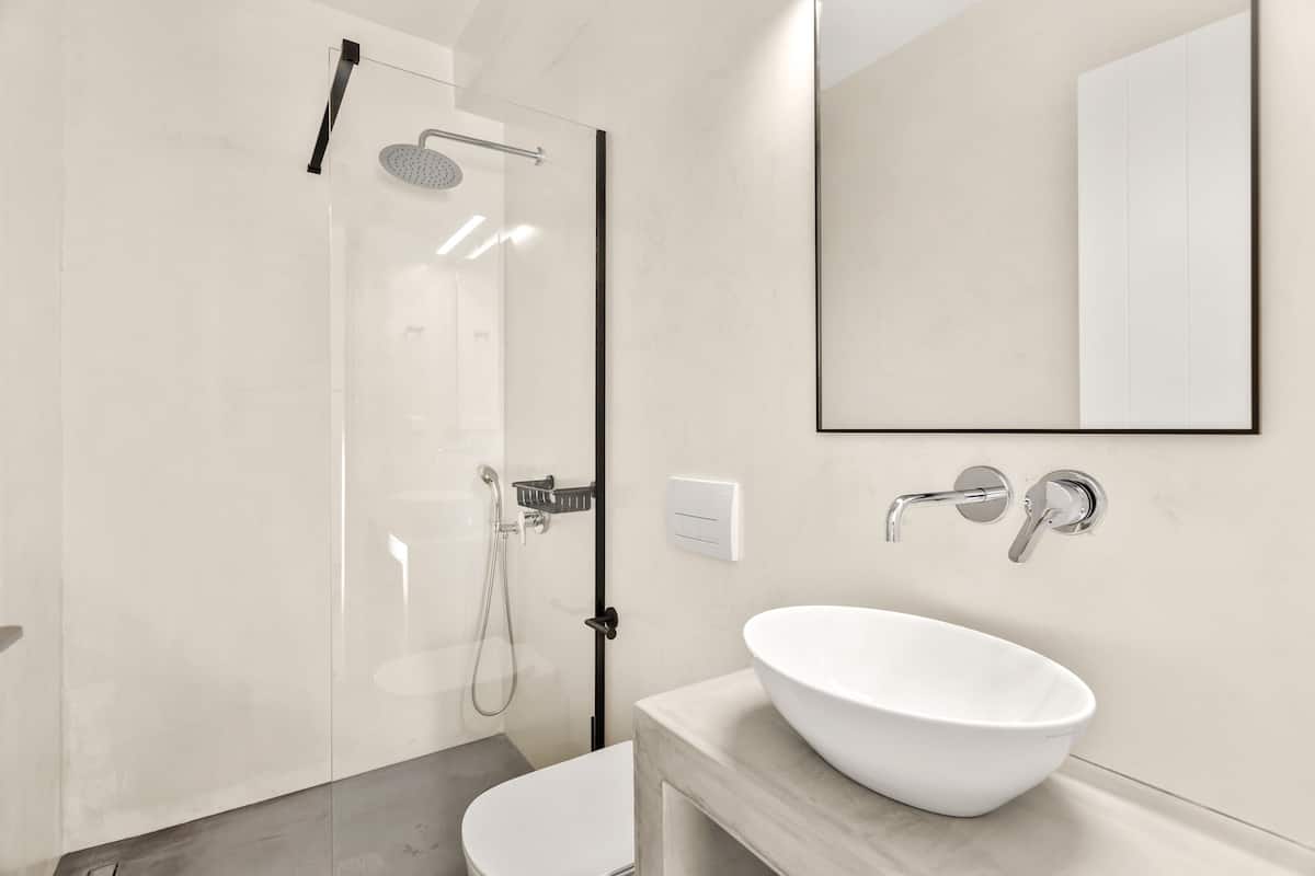 A modern bathroom with a glass shower enclosure, a white sink, and a large mirror.