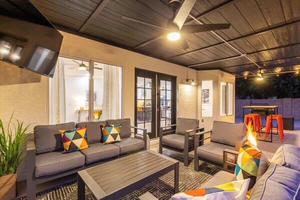 An outdoor patio area with a sofa, chairs, a table, and a fire feature.