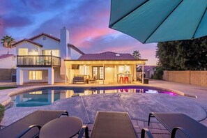 A modern house with a swimming pool, outdoor seating, and a covered patio.