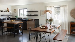 A modern kitchen with a wooden island, bar stools, and a dining table with benches.