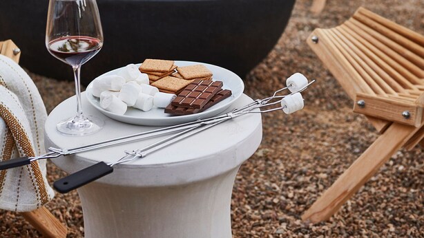 A fire pit with seating and a table with snacks and a glass of wine.