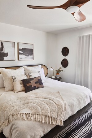 A neatly arranged bedroom with a bed, bedside tables, and wall art.