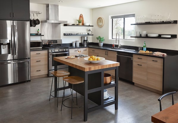 A modern kitchen with a central island, stainless steel appliances, and wooden accents.