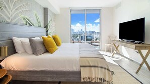 Une chambre d’hôtel moderne avec un grand lit, une télévision et une vue sur la ville par la fenêtre.