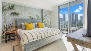 Une chambre moderne avec un grand lit, un bureau et un balcon offrant une vue sur la ville.