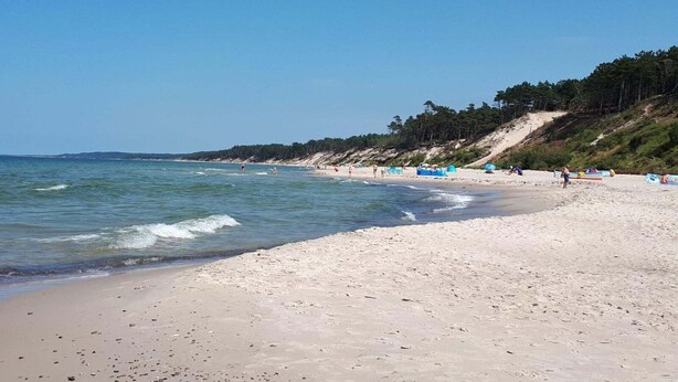 Een strand met heldere lucht, rustig water en een zandstrand.