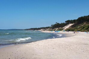 A beach with clear skies, calm waters, and a sandy shore.