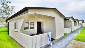 Een rij witte stacaravans met een veranda en een bordje met het nummer 3.