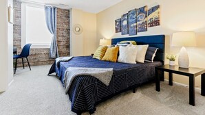 A bedroom with a bed, bedside tables, a chair, and artwork on the wall.