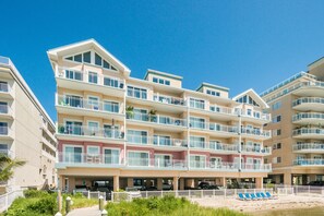 Un hotel de varios pisos con balcones, zona de estacionamiento y vista al mar.